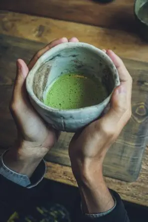 A handmade ceramic bowl filled with whisked matcha